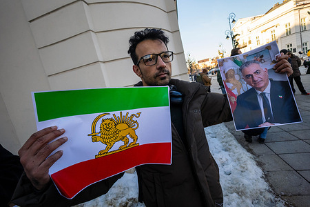 A protester holds a placard of the flag of the Iranian Crown and a picture of the Crown Prince of Iran, Reza Pahlavi. On the afternoon of 17th January, accompanied by Polish supporters, protesters of the Iranian diaspora gather outside the Presidential Palace in Warsaw, Poland. Following the recent anti-government protests in Iran, the demonstrators rally demanding an end to the violence of the Islamic Republic, and regime change to return the monarchy, which would install the Crown Prince of Iran, Reza Pahlavi, the son of the deposed Shah. The rally includes singing, chanting, dancing, and the waving of flags.