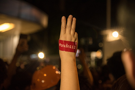 A protester makes a three finger salute with a message sticker "Abolish 112" during the demonstration. 
Pro democracy protesters gathered at Pathum Wan Intersection demanding to reform the monarchy after the Constitutional Court ruled that three protest leaders (Anon Nampa, Panusaya "Rung" Sithijirawattanakul, Panupong "Mike" Jadnok) aimed to overthrow the monarchy during their mass rally calling for political and monarchy reform in Thailand.