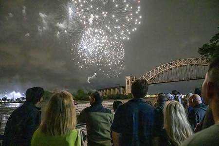 Spectators watch fireworks explode over the Hell Gate Bridge during the Central Astoria annual Independence Day Celebrations fireworks display in Astoria Park on June 26, 2025 in the Queens borough of New York City.