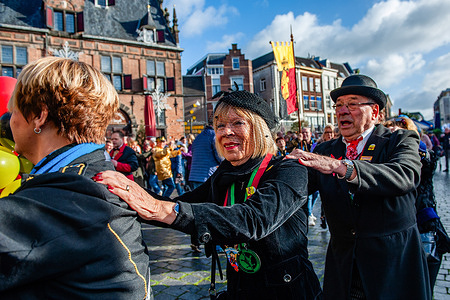 A couple is seen following people dancing. Every year, on November 11th, at 11:11 pm, people gather in the center to count down and celebrate the beginning of the Carnival season. From this day, a council of eleven meets to discuss the upcoming carnival events.