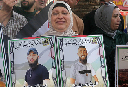 A mother of Palestinian prisoners weeps as she holds pictures of her imprisoned sons during a solidarity rally. Palestinians held a protest to demand a prisoner exchange agreement with the Israeli government and Hamas and an end to the ongoing war in the Gaza Strip between Hamas and Israel.