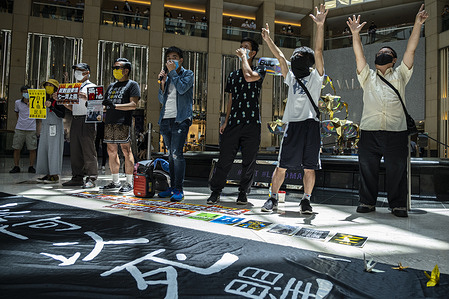 Demonstrators hold placards, gesturing and shouting slogans during a rally against the new national security law in a shopping mall.