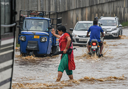 A woman walks through a waterlogged stretch after heavy rains in Guwahati. The India Meteorological Department (IMD) has forecast heavy rains with thunderstorms and lightning over the northeast region for the next two days.