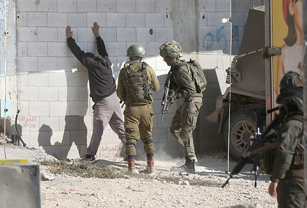 Israeli soldiers search a Palestinian man at an Israeli army checkpoint at the entrance to the camp as he tries to retrieve his belongings, while the Israeli army continues its attacks on the Nur Shams camp In the city of Tulkarm in the West Bank