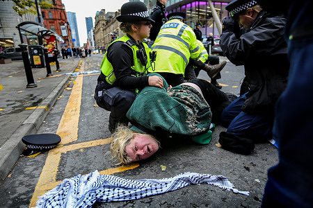 A Palestine Action activist is wrestled to the ground by police officers, handcuffed and arrested outside the Fisher German offices. Palestine Action occupy the glass roof of property giant Fisher German. Fisher German lease and manage the factory used by Elbit System’s UAV Engines in Shenstone, Staffordshire. UAV Engines manufactures engines for drones including the Hermes 450, a surveillance drone also capable of carrying missiles. Palestine Action argue these drones and others are being used to kill Palestinians in Gaza and elsewhere. Palestine Action demands that arms companies like Elbit Systems and their partner companies stop providing weapons for Israel and shut down permanently. They have recently been targeting a number of companies with direct action which led to Fisher German closing their Birmingham office. These actions are intended to highlight the plight of Palestinians in Gaza and the West Bank but also disrupt the manufacturing in those businesses. Palestine Action have declared they will not stop their actions until the arms industry stops supporting Israel.