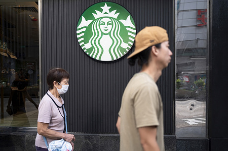 Pedestrians walk past the American multinational chain Starbucks Coffee store.