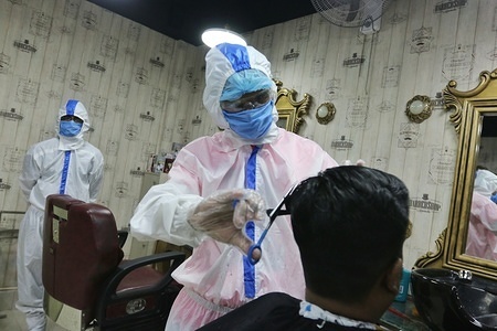 A barber dressed in a protective suit as a preventive measure trims a man's hair as businesses reopen.
Bangladesh government announced that certain businesses including: super shop, shopping mall, stationary, hair salons, barbershops could reopen. There are currently over 20,000 confirmed COVID-19 cases with 314 deaths.