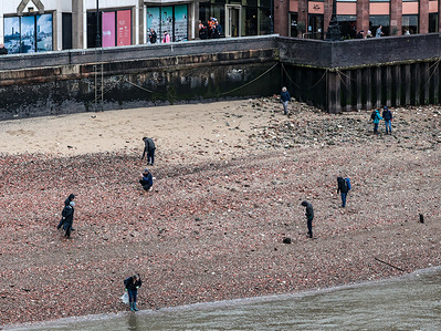 People search for mules by the river Thames during the rainy low tide in central London.