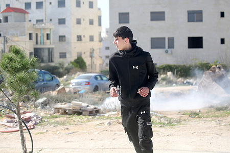 A Palestinian youth flees from tear gas fired by Israeli forces during the demolition of a house in the al-Ta'awun neighborhood of Nablus in the West Bank. The Israeli army also demolished three other Palestinian homes, claiming they were built without permits and in areas under Israeli control.