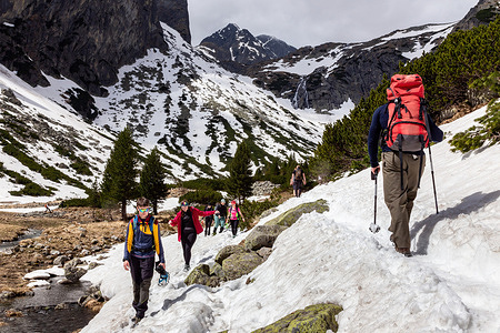 Tourists walk on a hiking trail dressed in relatively light clothes amid picturesque views in Mala Studena Valley, High Tatra mountain range (Vysoke Tatry) in northern Slovakia.