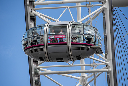 People look out from the cabin of the London Eye to see panoramic views. The London Eye is originally the Millennium Wheel a cantilevered observation wheel on the South Bank of the River Thames. It is 135 metres (443 ft) tall and the wheel has a diameter of 120 meters (394 ft). It makes the world's tallest cantilevered observation wheel and the most popular paid tourist attraction in the country.