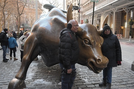 People take photos by the "Charging Bull" statue in the Financial District in Manhattan, New York City.