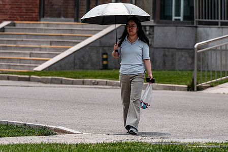A woman walking with a parasol and a mobile phone. China's mobile phone subscriber base reached 1.827 billion, with a penetration rate of 130 subscriptions per 100 people. Among them, 5G mobile phone subscribers numbered 1.204 billion, accounting for 65.9% of the total, making 5G the dominant connectivity method.