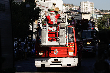 A firefighter is carried on a truck with an elevating platform during the Christmas Caravan in the city of Valparaiso, Chile. The volunteer fire department of the city of Valparaíso, Chile, is holding its traditional Christmas Caravan in the Port City area.