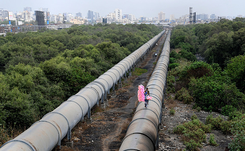 A cotton candy seller is seen walking on a water pipe in Mumbai.