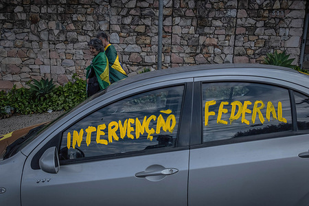 Supporters of the far-right Brazilian president Jair Bolsonaro wrapped in Brazilian national flags walk in front of a car with inscription asking for federal intervention during the demonstration. Hundreds of people took part in protests around the country to ask for federal intervention and contesting the results of the past October 30th elections that elected the left-wing candidate Luis Inacio Lula da Silva as the new Brazilian president. Scenes of political violence have been reported since the night of Sunday, when the final numbers were revealed.