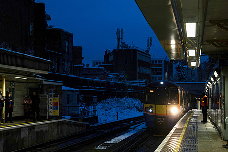 London Overground train seen running past a snowy station in the early morning. London has embraced the first snow of this winter overnight due to the arctic freeze and transportation are severely disrupted on Monday morning. Temperature were set below zero for the last few days and the Met Office issued a yellow warning of snow and ice till Tuesday morning for London and the Southeast England. London has embraced the first snow of this winter overnight due to the arctic freeze and transportation are severely disrupted on Monday morning. Temperature were set below zero for the last few days and the Met Office issued a yellow warning of snow and ice till Tuesday morning for London and the Southeast England.