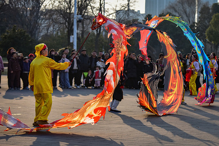 A performer creates a stunning circular pattern with a fiery-patterned ribbon dragon, amazing onlookers at Fuyang's Shuangqingwan South Square during Spring Festival. During the Spring Festival holiday, various folk performances are held across China to celebrate the Chinese New Year.