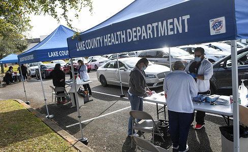 Health workers in tents administer the Pfizer COVID-19 vaccine to people in cars at a drive-thru vaccination event sponsored by the Lake County Health Department for persons 65 and older at the Clermont Arts and Recreation Center. Residents waited for as long as three hours at the first come, first served vaccination distribution event, while new daily coronavirus cases in Florida are currently at record levels.