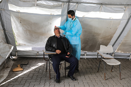 Palestinian health worker collects a swab sample from a man for COVID-19 testing during a mass COVID-19 testing.
The Palestinian Ministry of Health in the Gaza Strip has announced the first case of omicron variant in Gaza and said that this infection was transmitted from Israel to the Gaza Strip through a Palestinian worker who was working in Israel, Also they asked people to conduct early examination by withdrawing samples and receiving the necessary vaccinations against the COVID-19 pandemic.