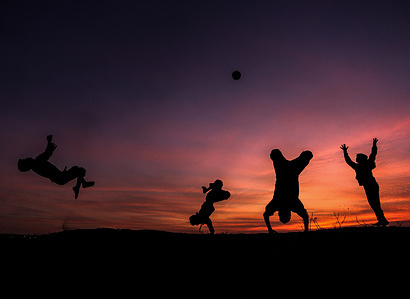 Silhouettes of Palestinian children playing gymnastics and football during sunset in Beit Lahia, northern Gaza Strip.