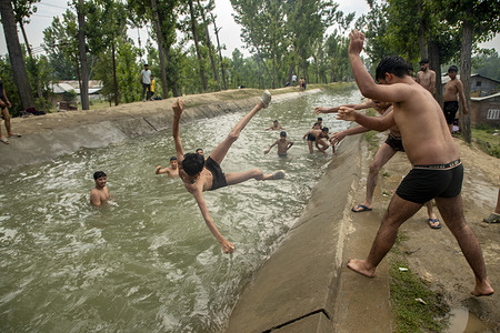 A Kashmiri boy jumps into a water canal to cool off from the scorching heat on a hot summer day in the outskirts Srinagar. The Himalayan region of Kashmir is experiencing an unusual heatwave in May, with Srinagar, the summer capital of Jammu and Kashmir, recording its highest temperature in the past 57 years at 34.4 degrees Celsius (93.92 degrees Fahrenheit), the third highest ever for the month. The local weather office has predicted an isolated heatwave across the region, stating that generally hot and dry weather is expected until May 26. Meanwhile, authorities have announced a change in school timings to help students cope with the extreme weather. Residents are advised to stay hydrated and avoid outdoor activities during peak hours.
