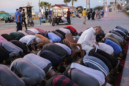 Palestinian Muslims pray along a coastal road in Gaza city.