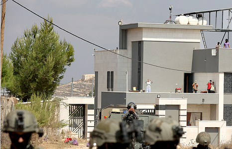 An Israeli soldier seen on guard outside a Palestinian home besieged by Israeli settlers in the village of Qusra. Israeli forces attacked the settlers who surrounded the Palestinian homes amid unprecedentedly sharp criticism from the United States. The forces surrounded Palestinian homes in Qusra including one owned by an American citizen. Residents say they have been prevented from accessing food and other supplies.