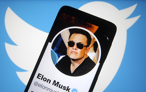In this photo illustration, the Twitter page of Elon Musk is seen on a smartphone screen and Twitter logo in the background. Elon Musk reaches a deal to buy Twitter Inc for $44 billion, reportedly by media.