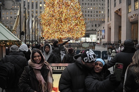 People take photos in front of the Rockefeller Center Christmas tree in Manhattan, New York City.