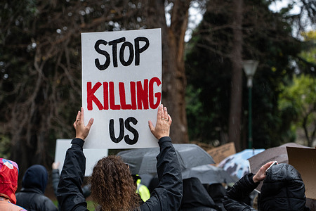 A protester holds a placard that says "stop killing us during the demonstration. Despite the rain people gathered to protest violence against women, after 54 women have been killed this year due domestic violence, the perpetrators of this violence mainly being men. The protesters are calling for the Australian Government to take action.