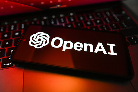 In this photo illustration, an OpenAI logo is displayed on a smartphone on top of a laptop.
