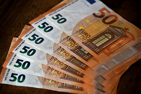 In this illustration photo, 50 euro banknotes are fanned out on a wooden table.