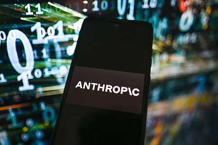 In this photo illustration, an Anthropic logo is seen displayed on a smartphone with stock market percentages on the background.