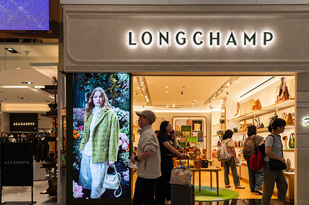 Pedestrians walk past a French luxury goods company Longchamp store at Taiwan Taoyuan International Airport.