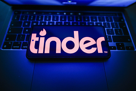 In this photo illustration, a Tinder logo is seen displayed on a smartphone on the top of a laptop.