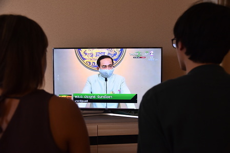 In this photo illustration, people watch Prime Minister, Prayut Chan-o-cha on tv during a press conference on the emergency stage that will begin on March 26 as a new measure against Covid-19 virus in Thailand.