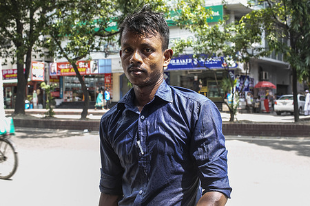 A man all sweating poses for a photo in the Street on a hot day in Dhaka.