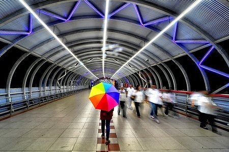 A model, Mousumi Das with a colorful umbrella seen walking on the Skywalk of Kalighat in South Kolkata for the Photo Series. The Photo Series is organized by a group of photographers from "Creative Art Solution", a registered photography club in India. Their aim is to document and promote the narrow lanes and streets adorned with beautiful color, graffiti , patterns at South Kolkata, as well as the rich heritage of the city. Model Mousumi Das collaborated with the photographers, posing to enhance the visual storytelling and highlight the charm of street art, making the series more vibrant and compelling.