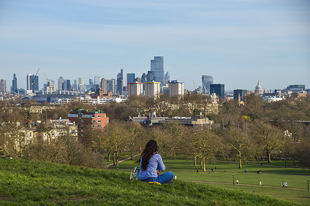 A woman enjoys the view from Primrose Hill in London on a sunny day.
