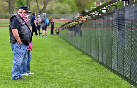 A veteran wearing a flag pattern mask looks at the Wall That Heals, a replica of the National Vietnam war memorial.
The Wall That Heals is a three-quarter scale replica of the Vietnam Veterans Memorial in Washington, D.C., the wall travels around the country and is set up and displayed for 24 hours a day while it is in place.