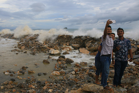 People seen taking selfies next to high waves on the coast of Susoh.
Increase in high waves and strong winds is expected during the rainy season according to a report by the Meteorology Climatology and Geophysics Agency (BMKG), on the coast of Susoh in Aceh Province, Indonesia.