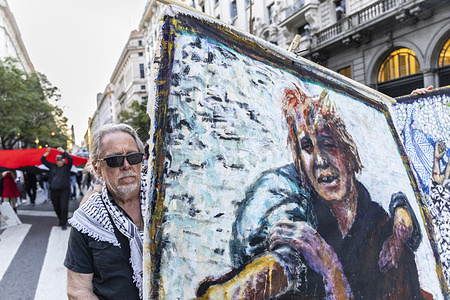 An artist carries a painting of a Palestinian child during the demonstration. The Argentine Committee in Solidarity with the Palestinian People called for a march to repudiate and condemn the genocide perpetrated in Gaza by the State of Israel. Social, political, and human rights organizations participated.