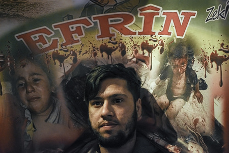 A protester seen in front of a placard at the demonstration.
Kurds living in Athens marched toward the Turkish embassy the protest against the genocide happening in Afrin.