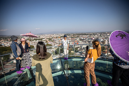MAE SAI, THAILAND - JANUARY 09: Local tourists take photos on the Mae Sai Skywalk in Mae Sai, Thailand on January 09, 2024. Newly built glass Skywalk at Phra That Doi Wao Temple in the Thai-Myanmar border town of Mae Sai in the northernmost of Thailand attracted local tourists as well as Myanmar tourists to experience the panoramic view of hills in Thailand and neighboring Myanmar and the city of Tachileik. The skywalk was officially inaugurated on November 9, 2023, and attracted as many as 10,000 visitors a day during weekends.