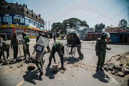 Anti-riot police remove boulders and burning tires barricading a road during the protest against the government and high cost of living called by Kenya's opposition leader Raila Odinga.