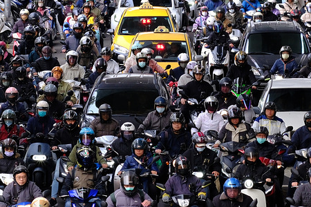Early morning commuters on motorbikes stop at the intersection during the rush hour. In Taipei, motorcycles are a very common means of transportation for commuting and going to school. The sight of roads being filled with motorcycles is often seen in the city especially during rush hours, bikes can be seen weaving through traffic. This mode of transport is popular because motorcycles can navigate through traffic more quickly and efficiently making them a convenient option for daily travel. Additionally, motorcycles have higher maneuverability compared to cars, making them ideal for the narrow streets and crowded areas in Taipei.