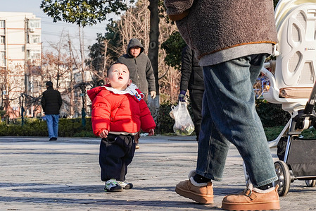 A toddler in a red puffer jacket looks up in surprise in Jingchuan Park. Data released by the National Bureau of Statistics of China on January 19 shows that in 2025, the per capita disposable income of Chinese residents nationwide reached 6,228.84 United States Dollar
(43,377 yuan), and the per capita consumer spending of national residents stood at 4,232.69 United States Dollar (29,476 yuan).