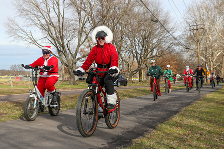 People in Christmas-themed costumes ride bicycles on the Bloomsburg Area Recreational Trail during the second annual Cycling Santa bike ride.