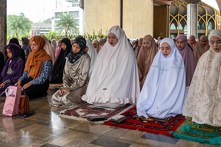 A close-up of Muslim women during prayer at the Foundation of the Islamic Centre of Thailand in Bangkok. Eid al-Fitr marks the end of Ramadan with a special morning prayer called Salat al-Eid, performed in congregation at mosques or open spaces. It is a time of gratitude, charity, and celebration with family and community.
